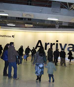 distance photo of meathrow airport arrivals lounge with people arriving travel and our airport taxis cab driver awaiting his booked client